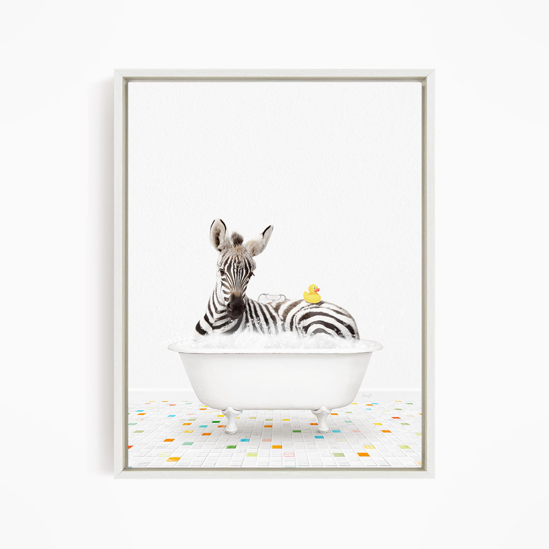 A zebra is sitting in a white bathtub, surrounded by a yellow rubber duck and a yellow rubber ducky.