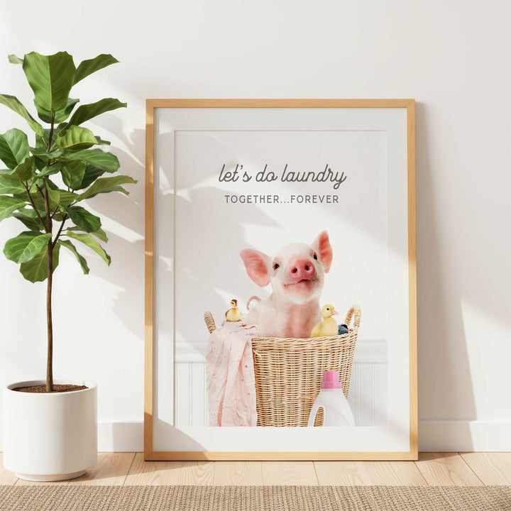 A framed poster with a pig sitting in a basket filled with various items, including a bottle of detergent and a yellow duck.