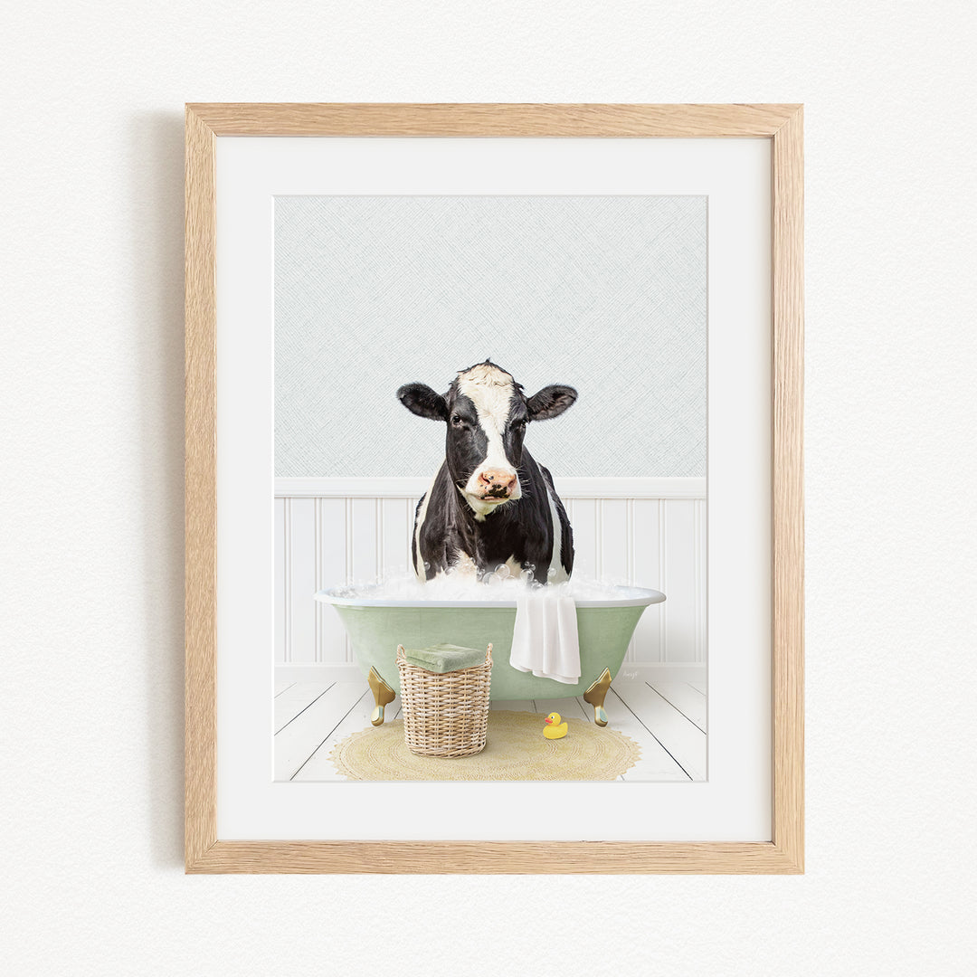 A black and white cow is sitting in a green bathtub filled with water, surrounded by rubber ducks and a basket.