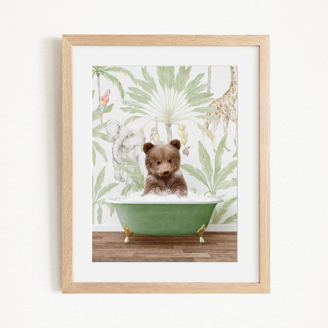 A framed image depicting a small brown bear sitting in a green bathtub, surrounded by a tropical jungle wallpaper.