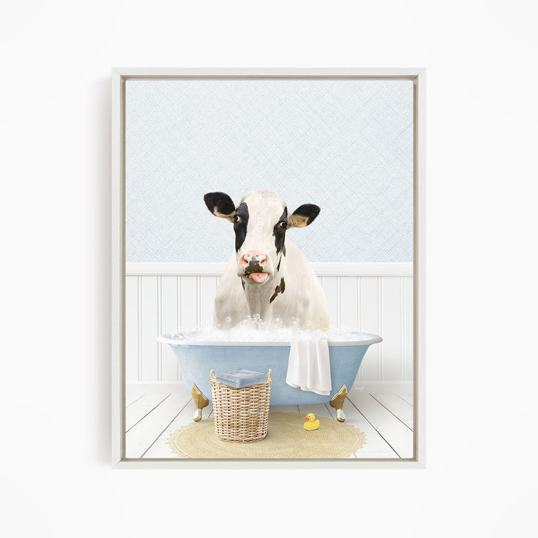 A black and white cow is sitting in a blue bathtub filled with water, surrounded by a yellow rubber duck and a basket.