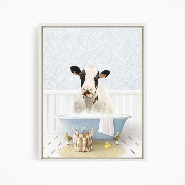 A black and white cow is sitting in a blue bathtub filled with water, surrounded by a yellow rubber duck and a basket.
