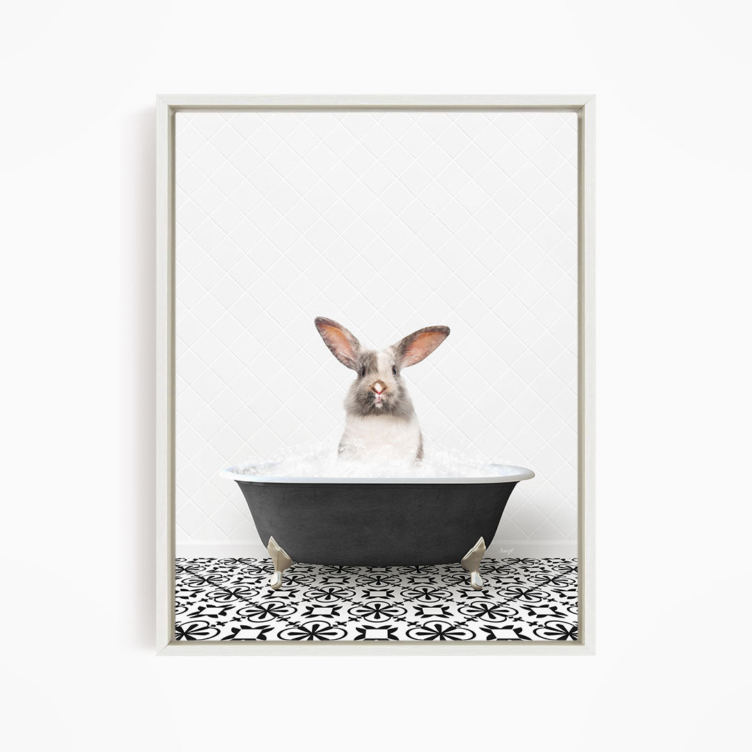 A white rabbit sitting in a black bathtub filled with water, looking directly at the camera.