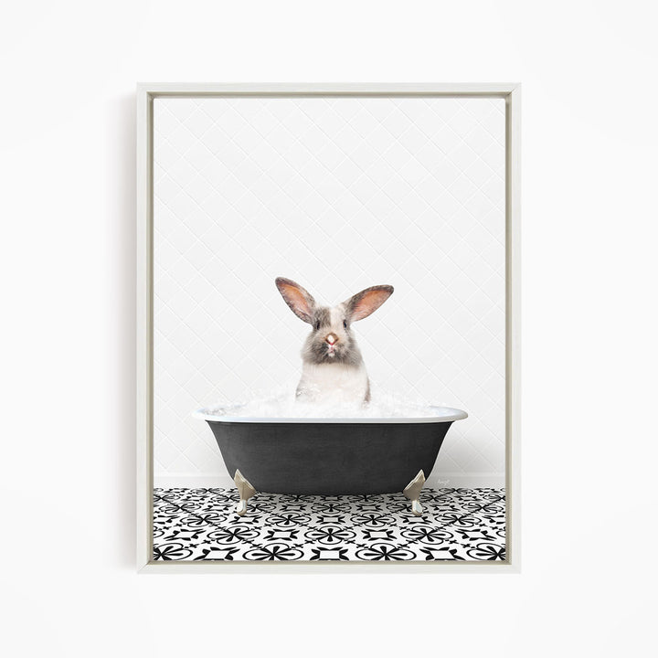 A white rabbit sitting in a black bathtub filled with water, looking directly at the camera.