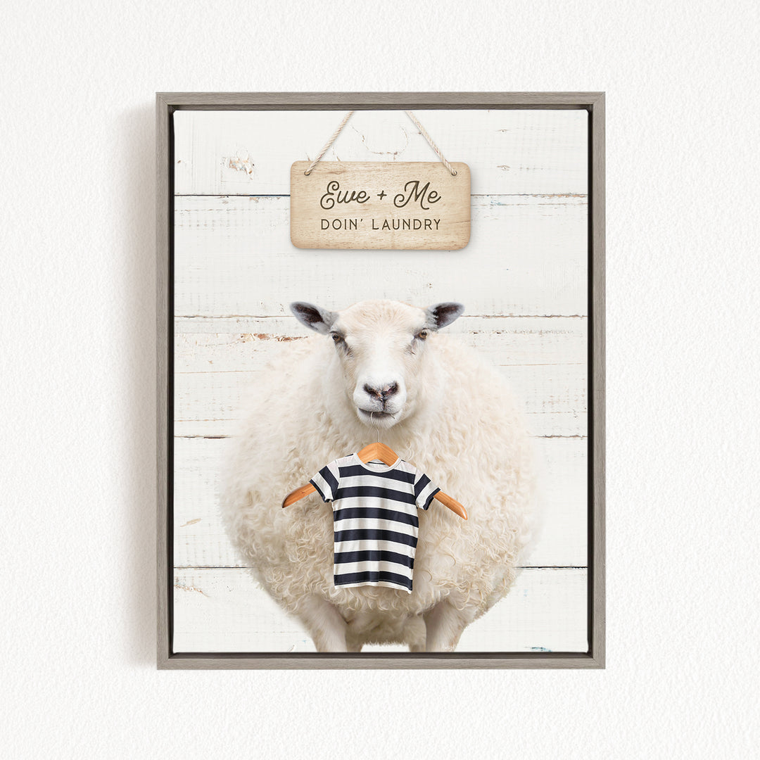 A framed image of a sheep wearing a striped shirt, with a sign above it that says "Eue + Me Doin' Laundry".