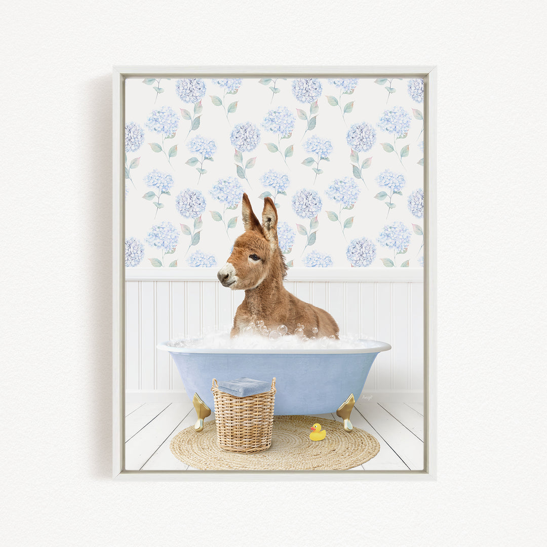 A donkey is sitting in a blue bathtub filled with water, surrounded by a wicker basket and a yellow rubber duck.