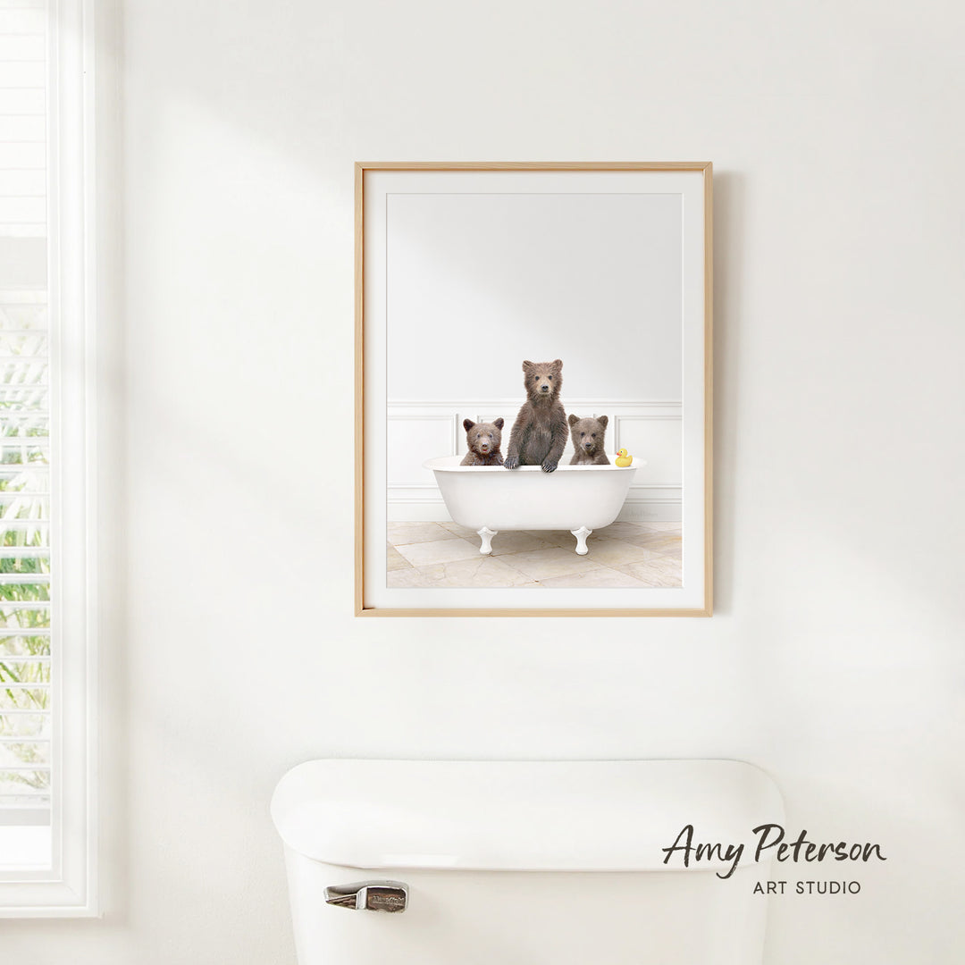 A framed image of three bears sitting in a bathtub, with one bear sitting on the edge of the tub and the other two bears sitting inside the tub.