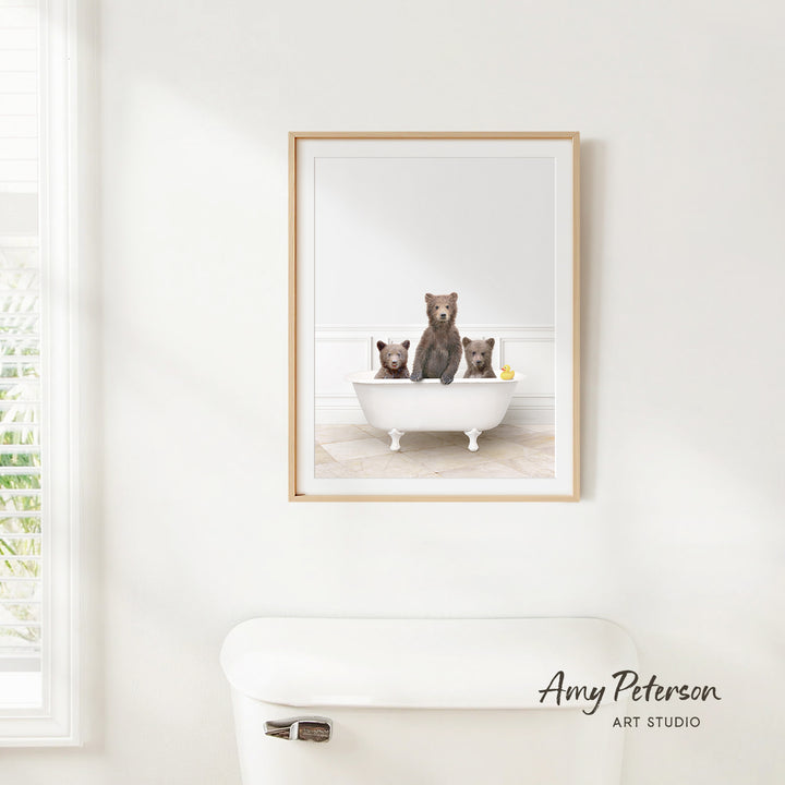 A framed image of three bears sitting in a bathtub, with one bear sitting on the edge of the tub and the other two bears sitting inside the tub.