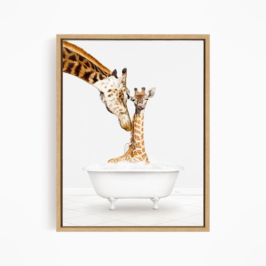 A mother giraffe and her baby giraffe are sitting together in a white bathtub, with the mother gently licking her baby.