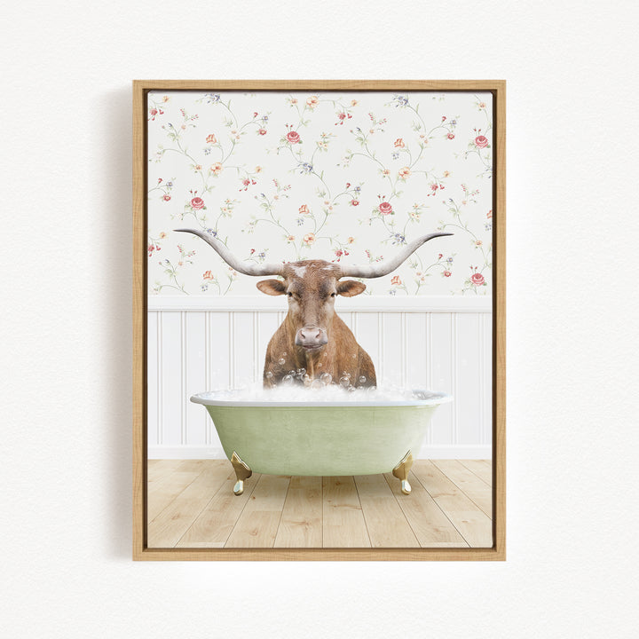A brown cow with large horns is sitting in a green bathtub filled with water, surrounded by a floral wallpaper.