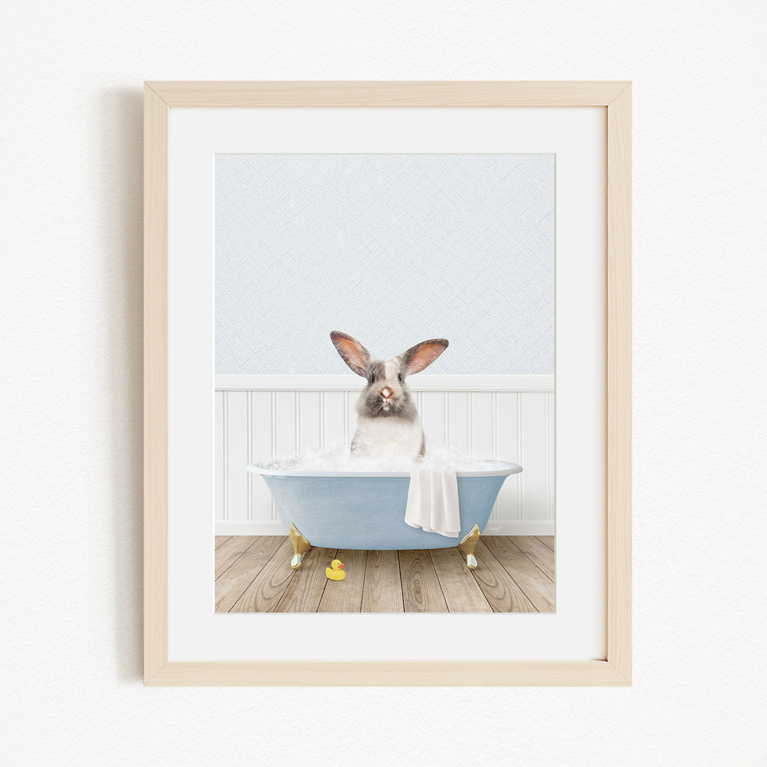 A white rabbit sitting in a blue bathtub filled with bubbles, with yellow rubber duckies floating around it.