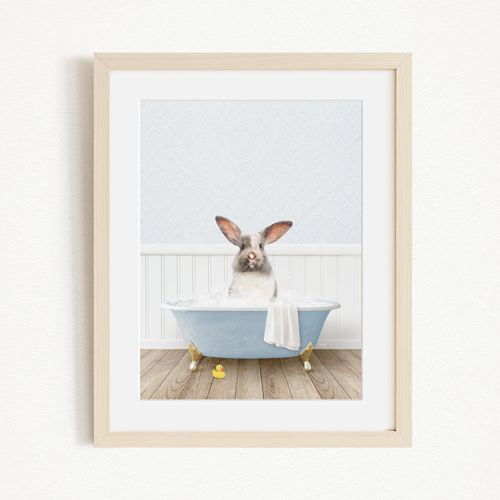 A white rabbit sitting in a blue bathtub filled with bubbles, with yellow rubber duckies floating around it.